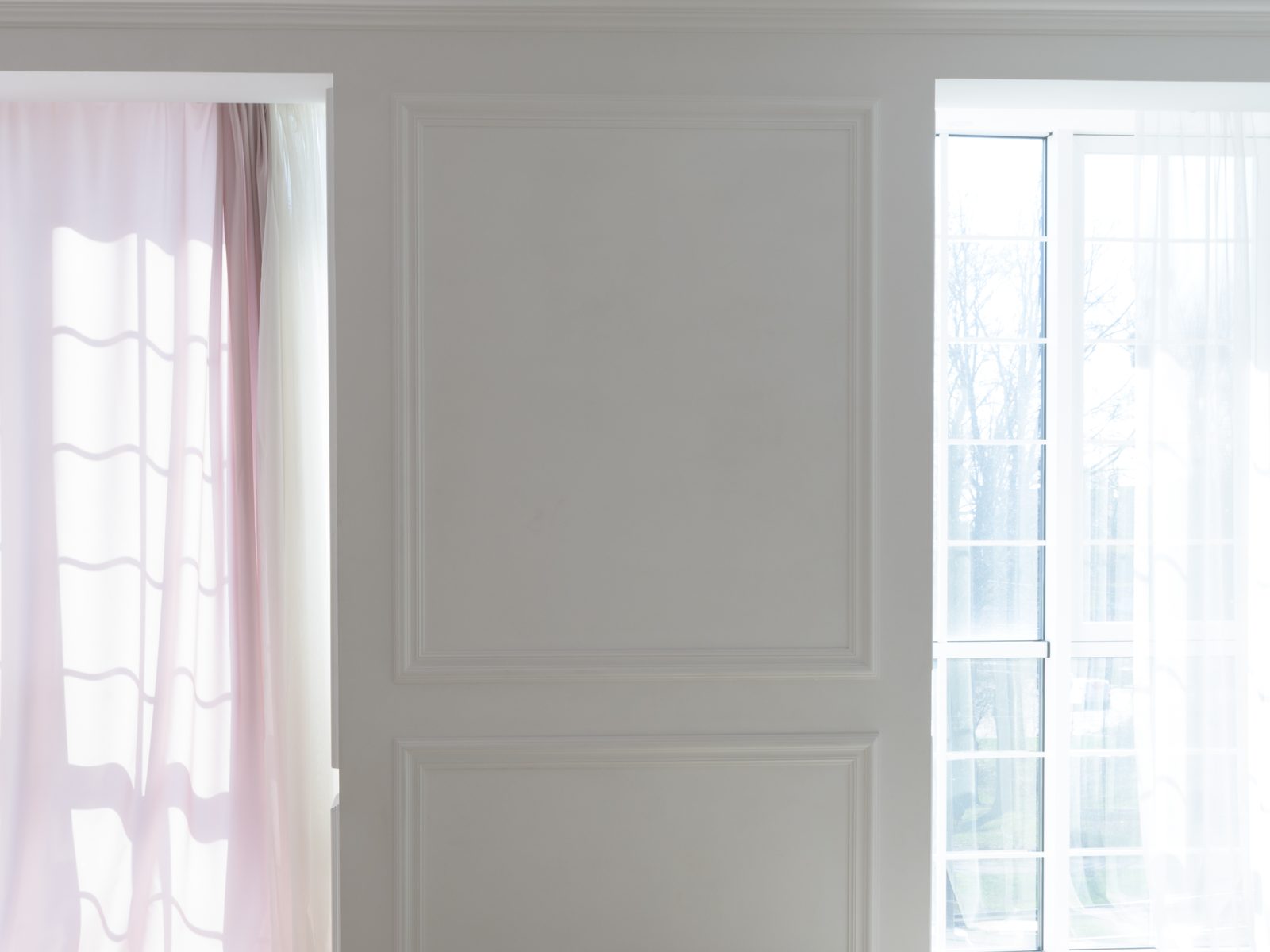 Un mur blanc à moulures entre deux fenêtres